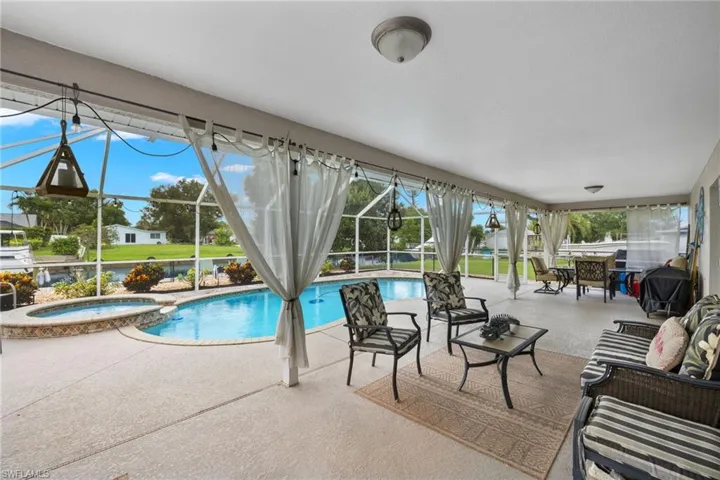 View of swimming pool featuring an in ground hot tub, a patio area, and a lanai