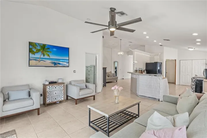 Living room with light tile patterned flooring, ceiling fan, and high vaulted ceiling