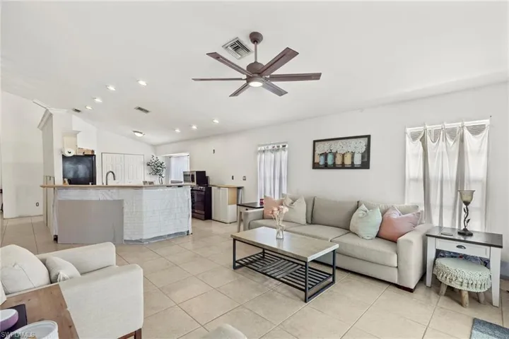 Tiled living room featuring sink, ceiling fan, and vaulted ceiling