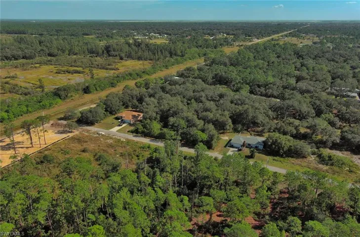 Aerial view of property and surrounding area with a forest