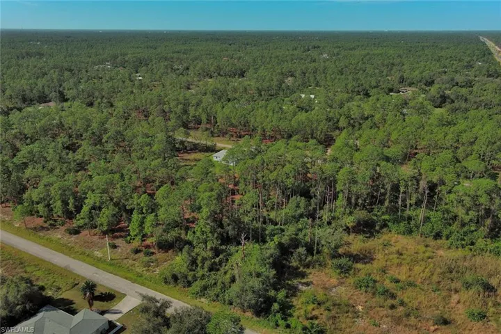 Aerial view of property and surrounding area featuring a forest