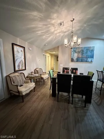 Dining room with vaulted ceiling, a chandelier, and hardwood / wood-style floors