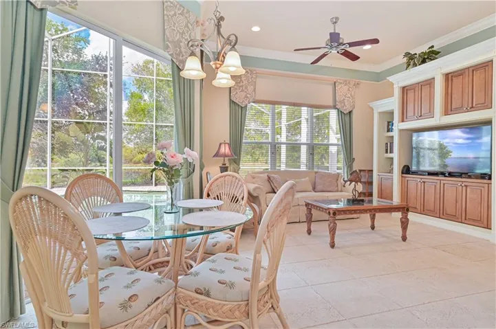 Dining area with ceiling fan, ornamental molding, light tile patterned floors, built in shelves, and hanging lights