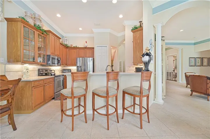 Kitchen with arched walkways, tasteful backsplash, stainless steel appliances, ornamental molding, and recessed lighting