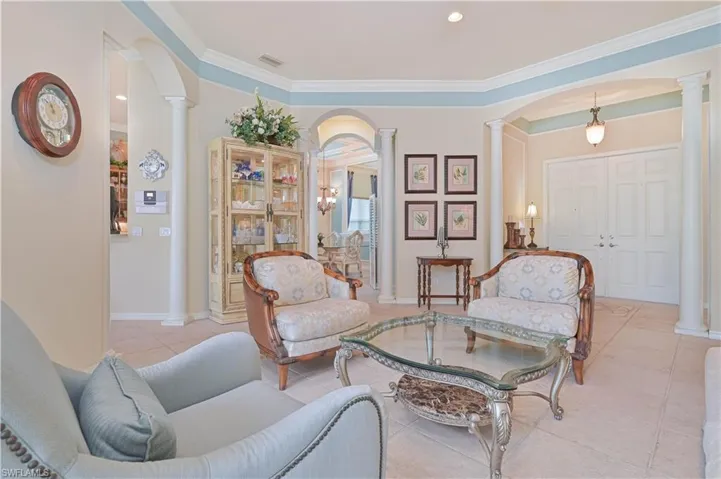 Living area with arched walkways, decorative columns, crown molding, light tile patterned flooring, and recessed lighting