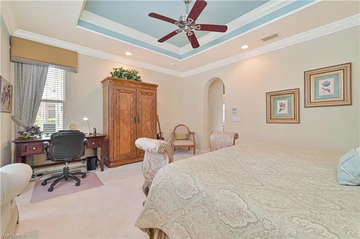 Bedroom featuring ornamental molding, light colored carpet, ceiling fan, arched walkways, and a desk