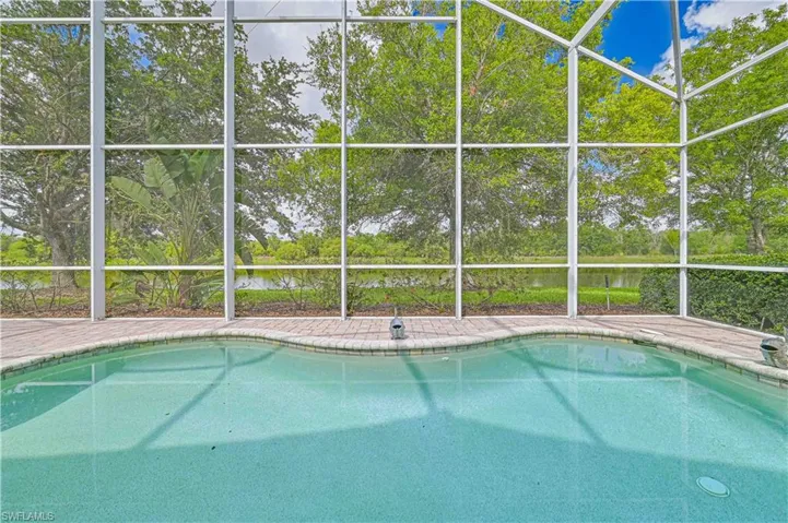 Outdoor pool with a lanai, a sunroom, and a water view