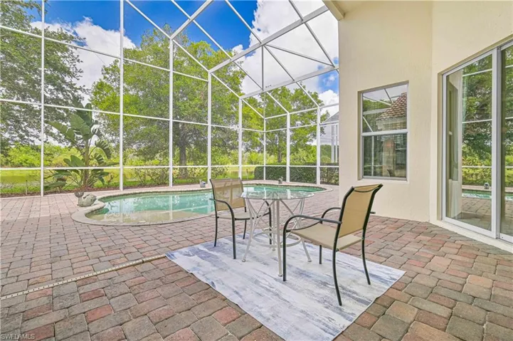 Outdoor pool featuring a patio, a sunroom, and glass enclosure
