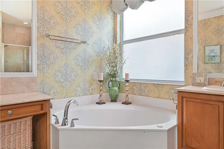 Full bath featuring a garden tub, vanity, wallpapered walls, and a stall shower