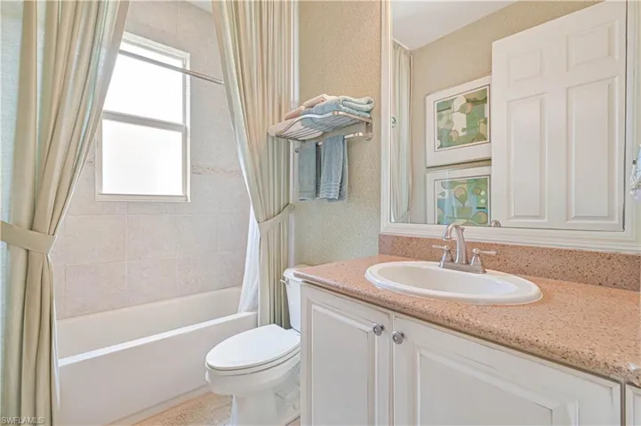 Full bath featuring vanity, shower / tub combo with curtain, and wallpapered walls