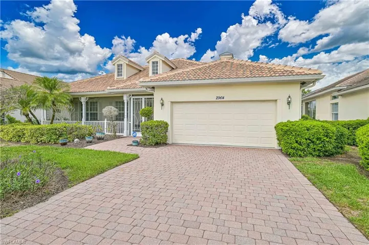 View of front of home featuring stucco siding, decorative driveway, a tiled roof, a garage, and a chimney