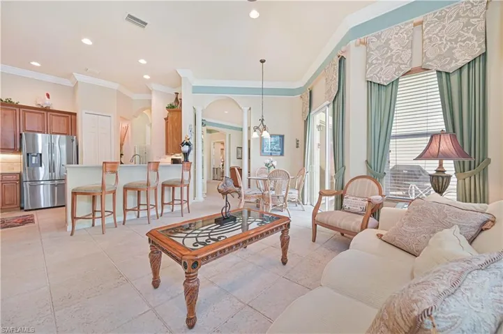 Living room featuring crown molding, arched walkways, recessed lighting, and light tile patterned floors