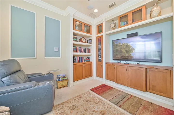 Living area featuring built in shelves, ornamental molding, light carpet, and recessed lighting