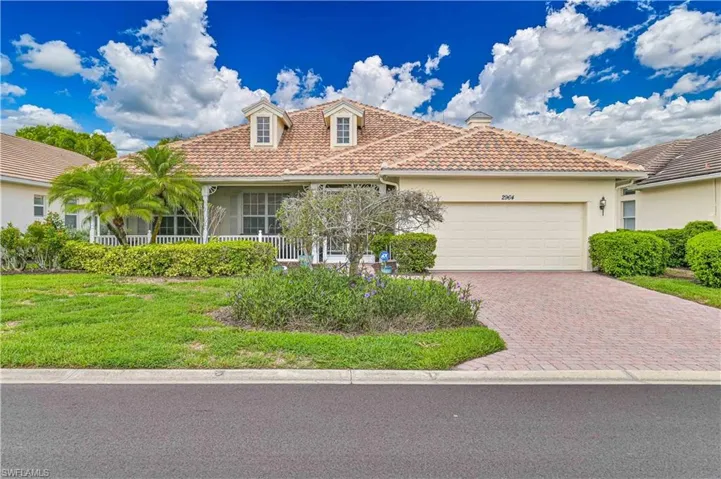 Mediterranean / spanish home with a tile roof, stucco siding, decorative driveway, an attached garage, and covered porch