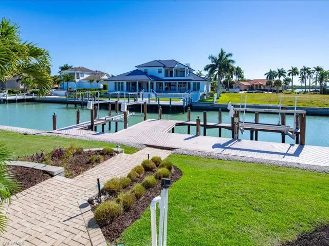 Dock featuring boat lift, a water view, and a lawn