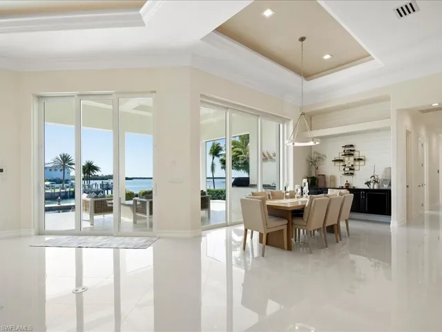 Building lobby with a raised ceiling, a water view, crown molding, and recessed lighting