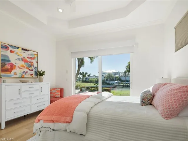 Bedroom featuring crown molding, access to exterior, light wood-style floors, a raised ceiling, and a ceiling fan