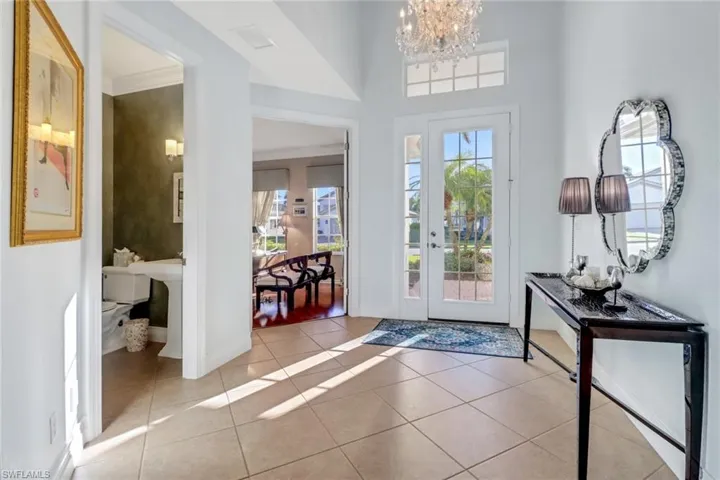 Entryway with crown molding, light tile patterned flooring, and a notable chandelier