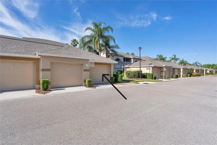 View of property with roof with shingles, stucco siding, a residential view, and community garages