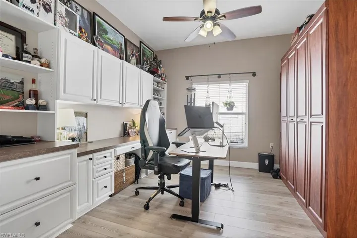 Office space featuring a ceiling fan, built in study area, light wood-style floors, and murphy bed