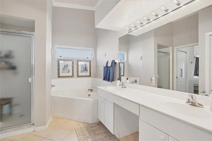 Full bath with a stall shower, double vanity, ornamental molding, tile patterned floors, and a bath