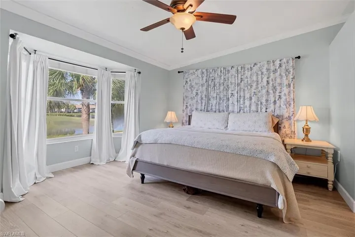 Bedroom with baseboards, crown molding, wood finished floors, lofted ceiling, and ceiling fan