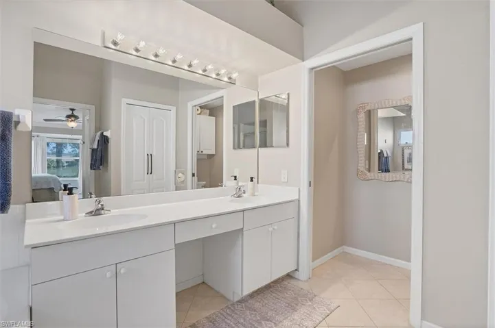 Full bathroom with double vanity, tile patterned floors, connected bathroom, and baseboards