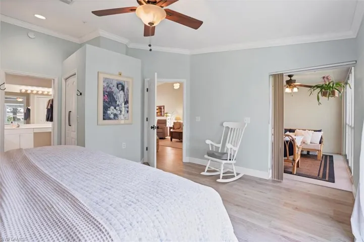Bedroom with light wood-style flooring, crown molding, connected bathroom, a ceiling fan, and baseboards