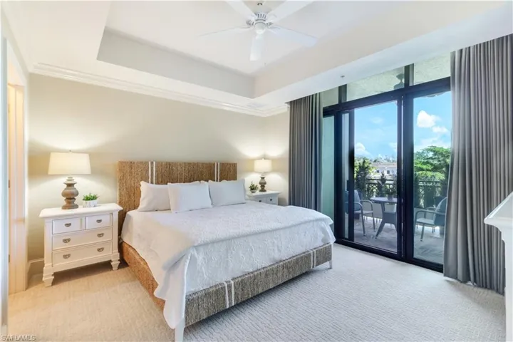 Bedroom with light carpet, access to outside, a raised ceiling, crown molding, and a ceiling fan
