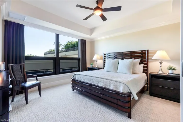 Bedroom with a tray ceiling, carpet, and a ceiling fan