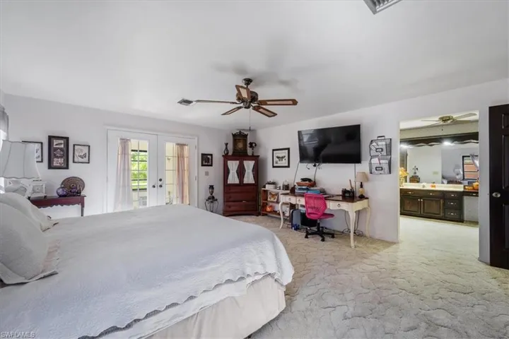 Carpeted bedroom featuring ceiling fan, access to exterior, and french doors