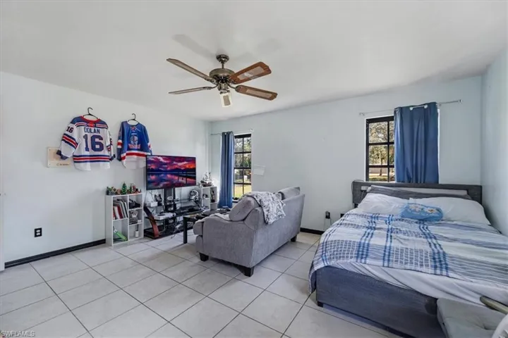 Bedroom with multiple windows, ceiling fan, and light tile patterned floors