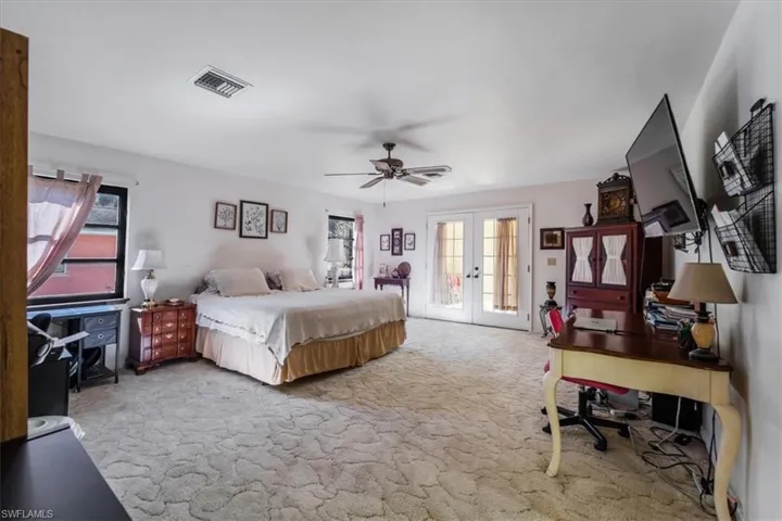 Bedroom featuring carpet flooring, multiple windows, ceiling fan, and french doors