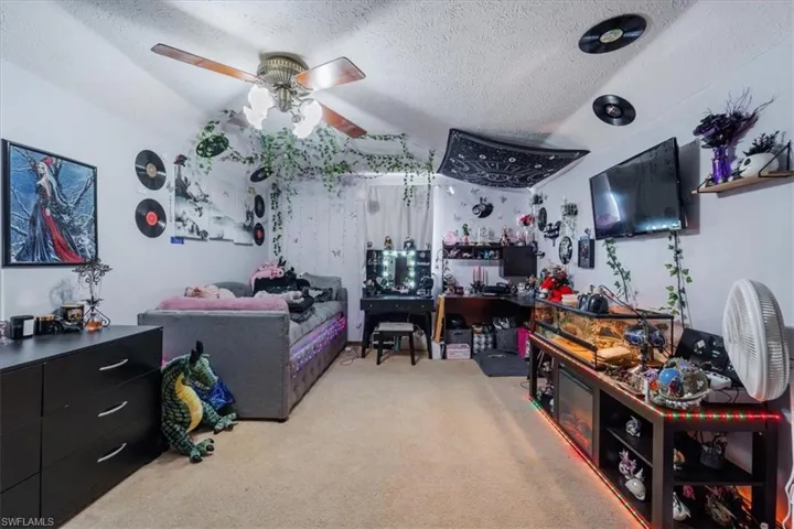 Carpeted bedroom featuring a textured ceiling and ceiling fan