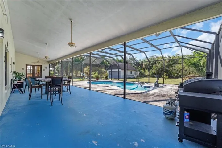 View of pool with glass enclosure, ceiling fan, a patio area, and french doors
