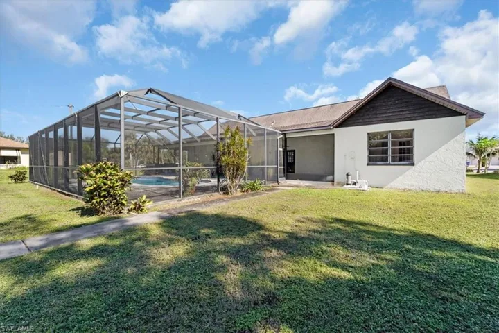 Back of property featuring glass enclosure and a lawn