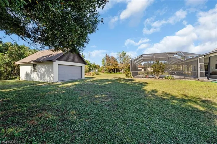 View of yard featuring glass enclosure, a garage, and an outdoor structure
