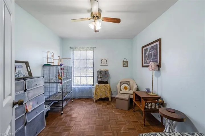 Sitting room featuring ceiling fan and dark parquet flooring