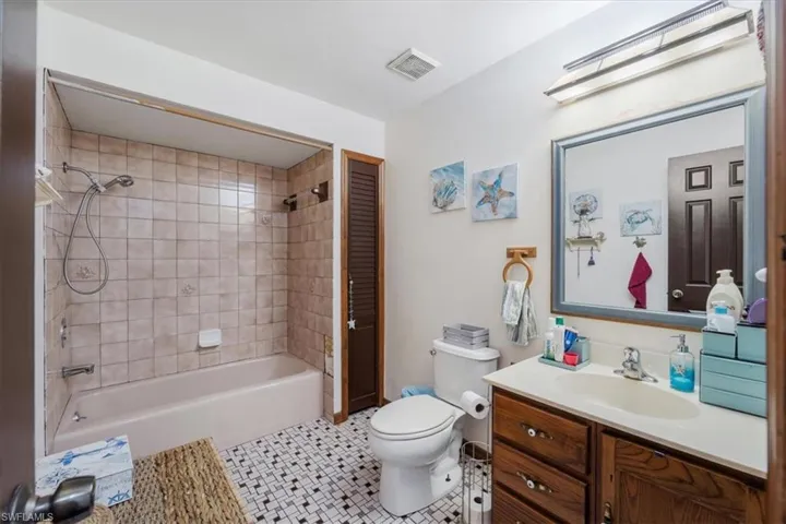 Full bathroom with tile patterned floors, vanity, toilet, and tiled shower / bath combo
