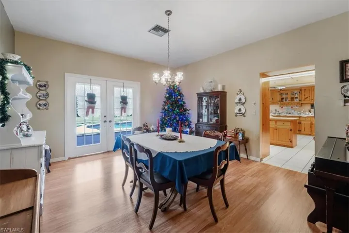 Dining area with light hardwood / wood-style flooring, french doors, and a notable chandelier