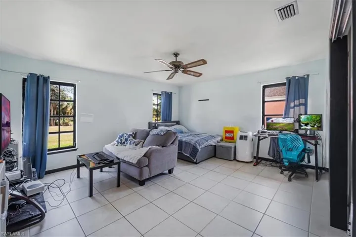 Bedroom featuring multiple windows, ceiling fan, and light tile patterned flooring