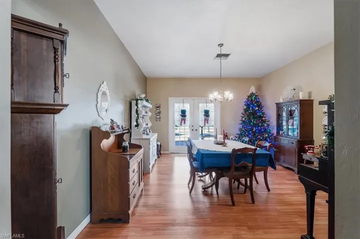 Dining area with french doors, light hardwood / wood-style floors, and an inviting chandelier