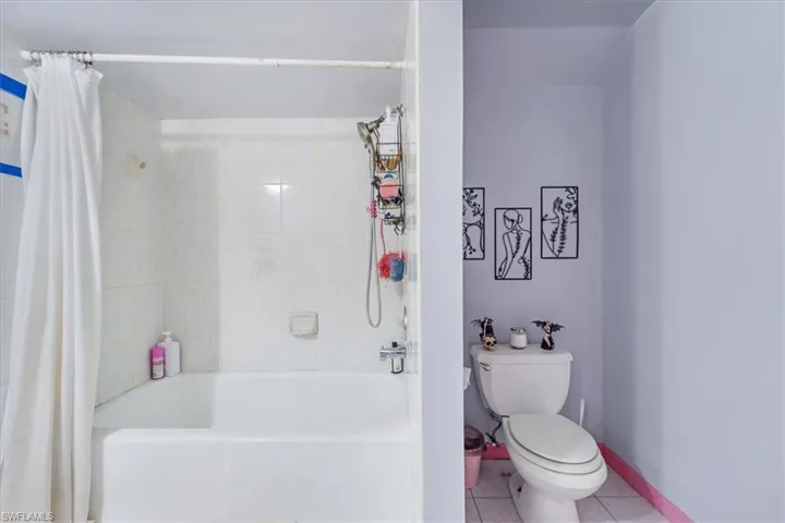 Bathroom featuring toilet, tile patterned floors, and shower / bath combo with shower curtain