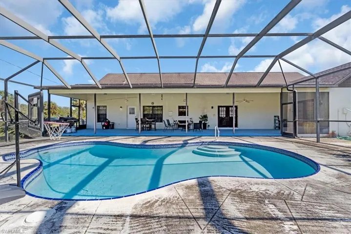 View of pool featuring ceiling fan, a patio area, and glass enclosure