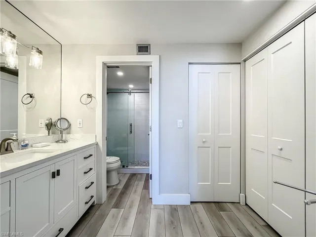 Bathroom with vanity, wood finish floors, a shower stall, and a closet