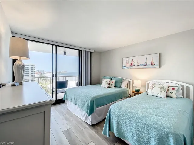Bedroom featuring floor to ceiling windows, light wood finished floors, and access to outside