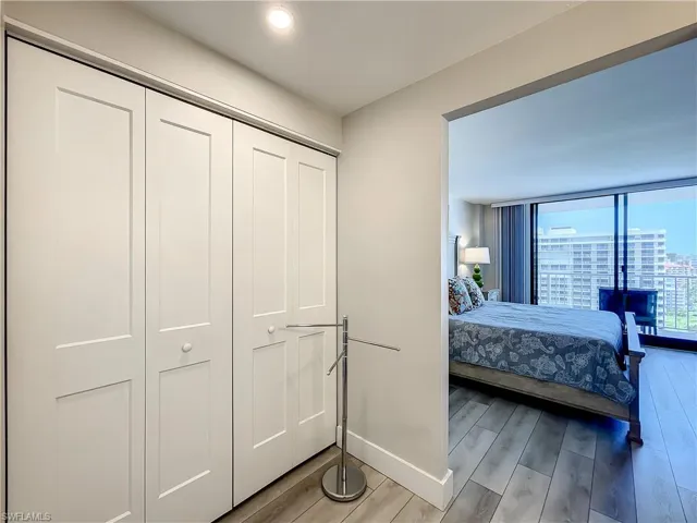 Bedroom featuring wood finished floors, a closet, expansive windows, and a view of city
