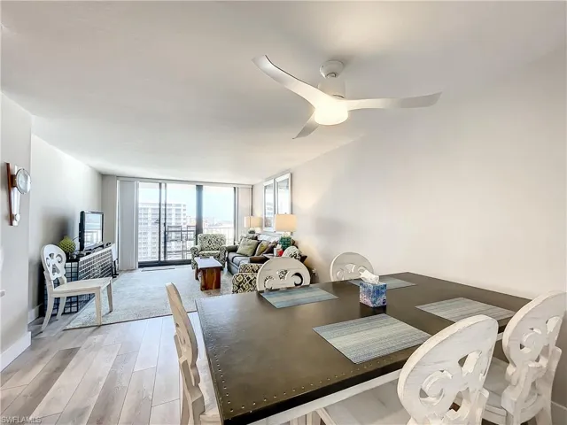 Dining space with a wall of windows, light wood finished floors, and a ceiling fan