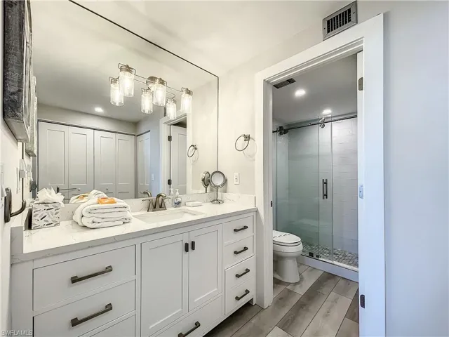 Bathroom with vanity, a shower stall, wood finish floors, recessed lighting, and a closet