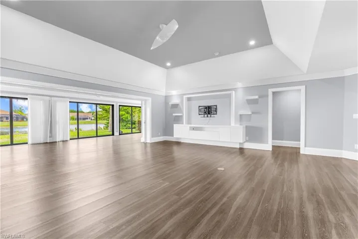 Expansive interior space featuring wood-finish flooring, a vaulted ceiling, and recessed lighting